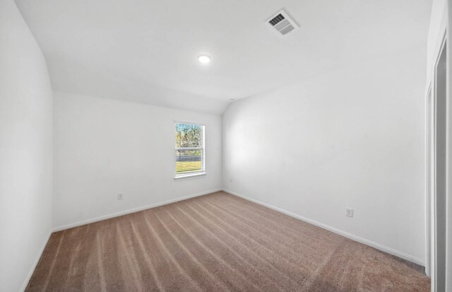 carpeted empty room featuring vaulted ceiling