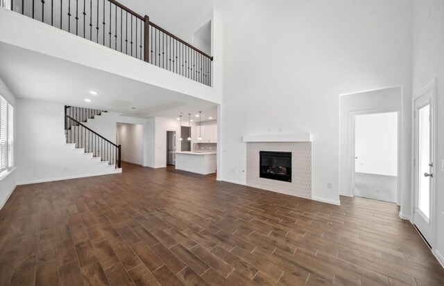 unfurnished living room with a wealth of natural light, a towering ceiling, and a brick fireplace