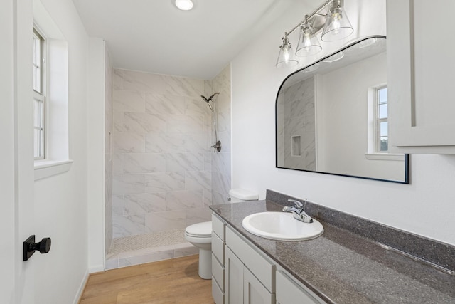 bathroom with hardwood / wood-style floors, vanity, a healthy amount of sunlight, and a tile shower