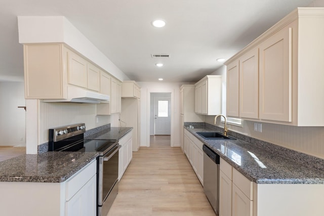 kitchen with dark stone countertops, light hardwood / wood-style floors, sink, and stainless steel appliances