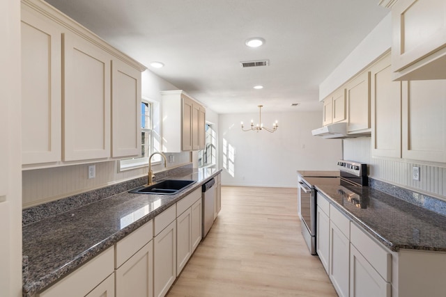 kitchen featuring an inviting chandelier, sink, hanging light fixtures, dark stone countertops, and appliances with stainless steel finishes