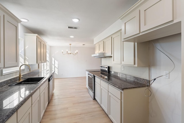 kitchen with an inviting chandelier, hanging light fixtures, sink, appliances with stainless steel finishes, and light hardwood / wood-style floors