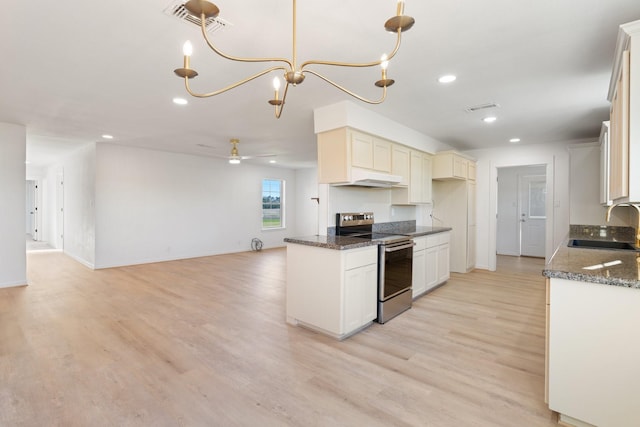 kitchen with dark stone counters, ceiling fan with notable chandelier, sink, hanging light fixtures, and stainless steel electric range