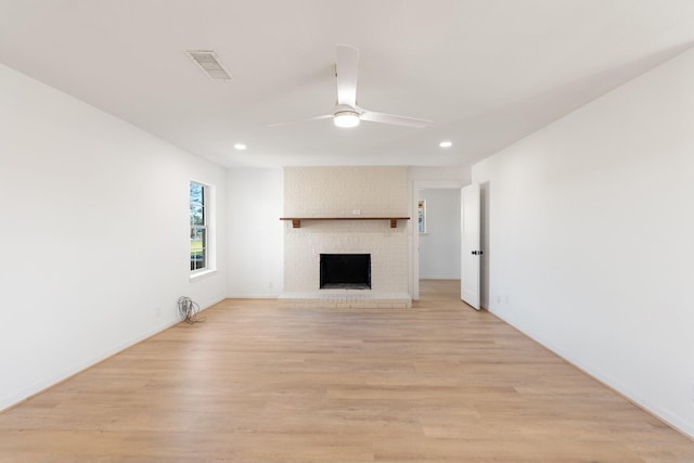 unfurnished living room with ceiling fan, light wood-type flooring, and a fireplace