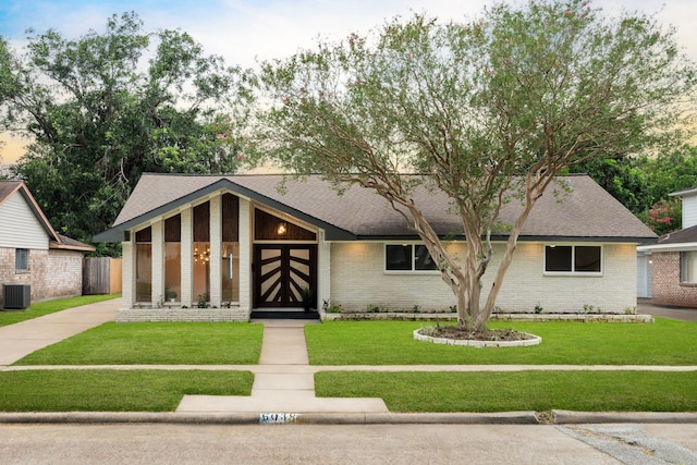 view of front of home with central AC and a front yard