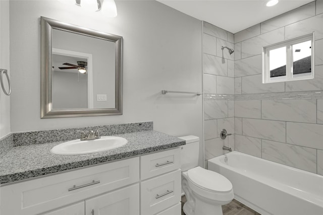 full bathroom with tiled shower / bath combo, ceiling fan, toilet, and vanity