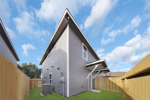 rear view of property with a lawn and cooling unit