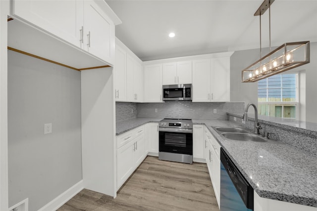 kitchen featuring light stone counters, stainless steel appliances, sink, decorative light fixtures, and white cabinets