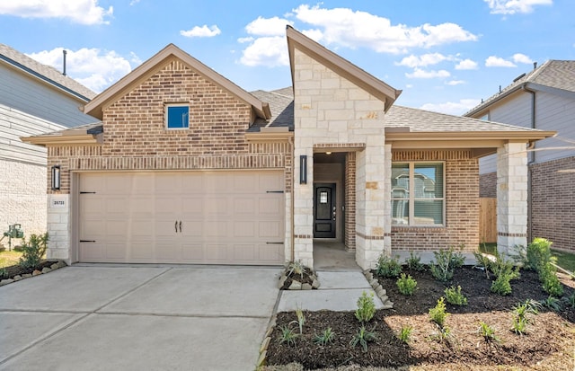 view of front facade featuring brick siding, roof with shingles, an attached garage, stone siding, and driveway