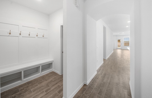 mudroom featuring arched walkways, wood finish floors, and baseboards