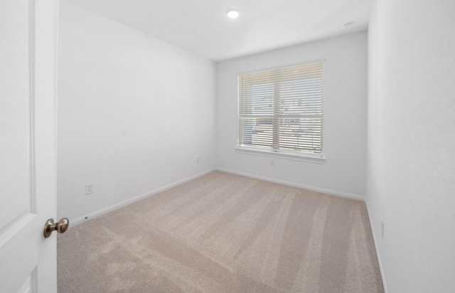 unfurnished room featuring light carpet and baseboards