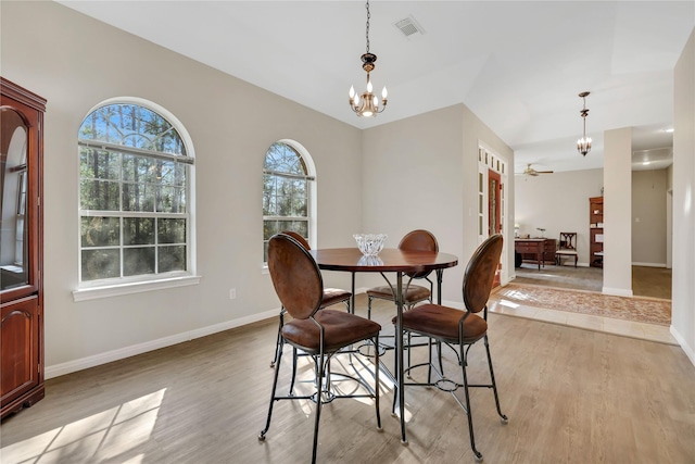 dining area with ceiling fan with notable chandelier and light hardwood / wood-style floors