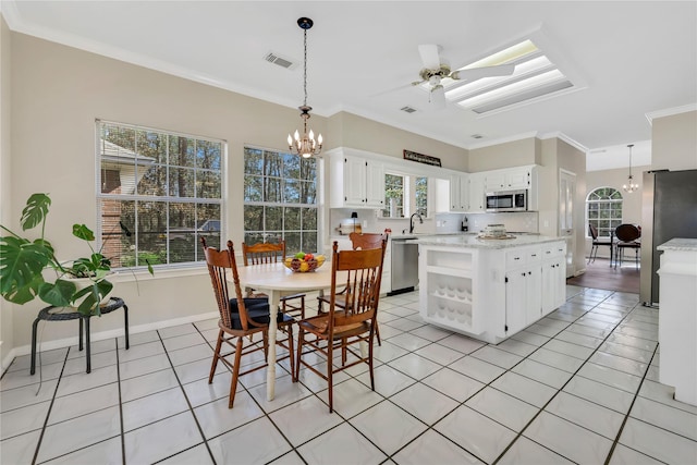 kitchen featuring pendant lighting, white cabinets, ceiling fan with notable chandelier, crown molding, and appliances with stainless steel finishes