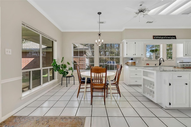 dining area featuring ceiling fan with notable chandelier, light tile patterned flooring, ornamental molding, and sink