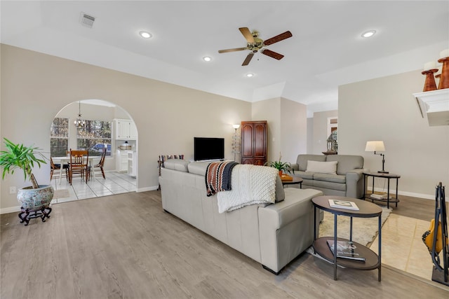 living room with ceiling fan with notable chandelier and light hardwood / wood-style flooring