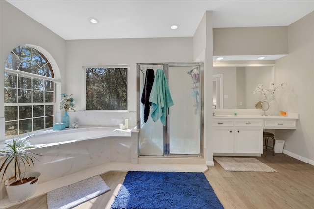 bathroom with wood-type flooring, vanity, and independent shower and bath