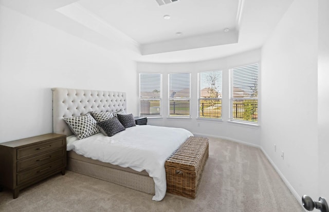 bedroom featuring light carpet and a tray ceiling