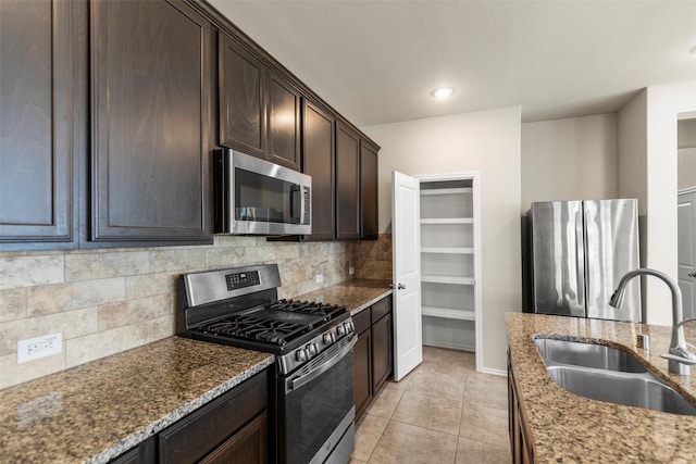 kitchen with dark brown cabinetry, light stone counters, sink, and stainless steel appliances