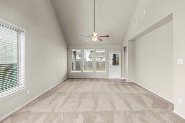 unfurnished living room featuring ceiling fan, light carpet, and a wealth of natural light