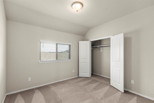 unfurnished bedroom with light colored carpet, vaulted ceiling, and a closet