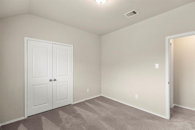 unfurnished bedroom with carpet, vaulted ceiling, and a closet