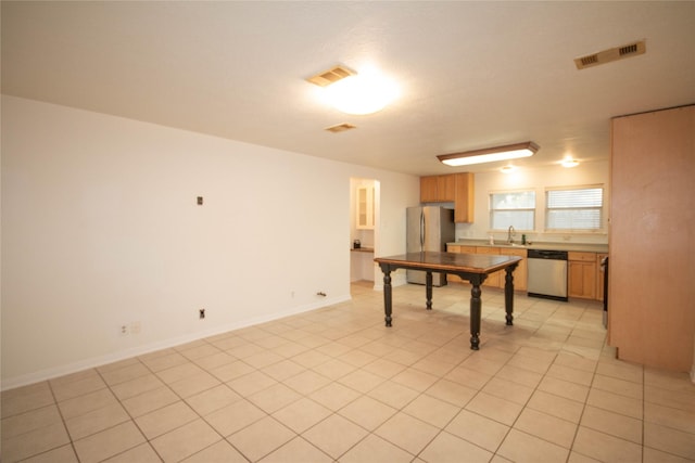 kitchen with appliances with stainless steel finishes, light tile patterned floors, and sink