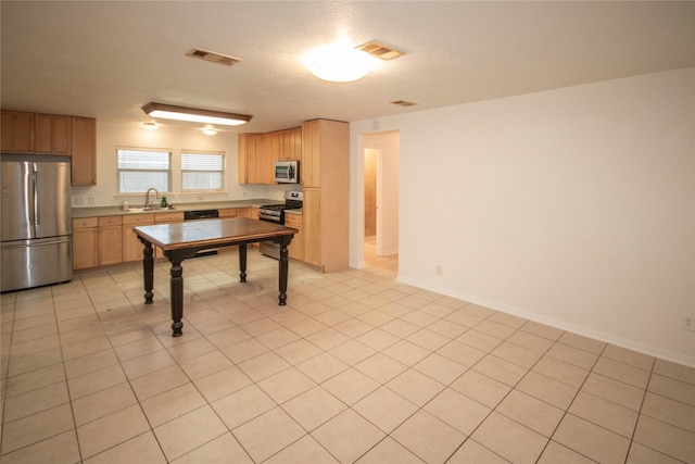 kitchen featuring a textured ceiling, light tile patterned floors, sink, and appliances with stainless steel finishes