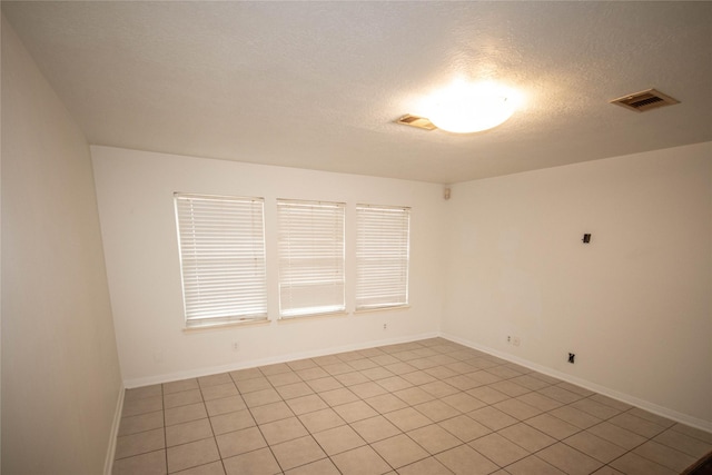 tiled empty room with a textured ceiling