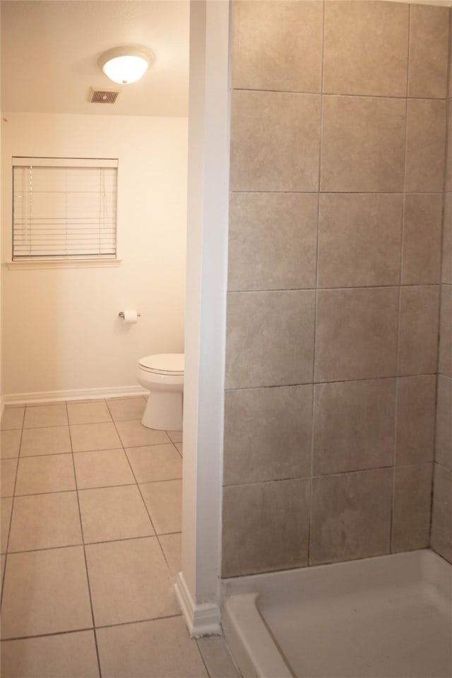 bathroom featuring tile patterned flooring, toilet, and walk in shower