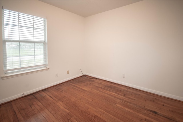 empty room with hardwood / wood-style floors and a healthy amount of sunlight