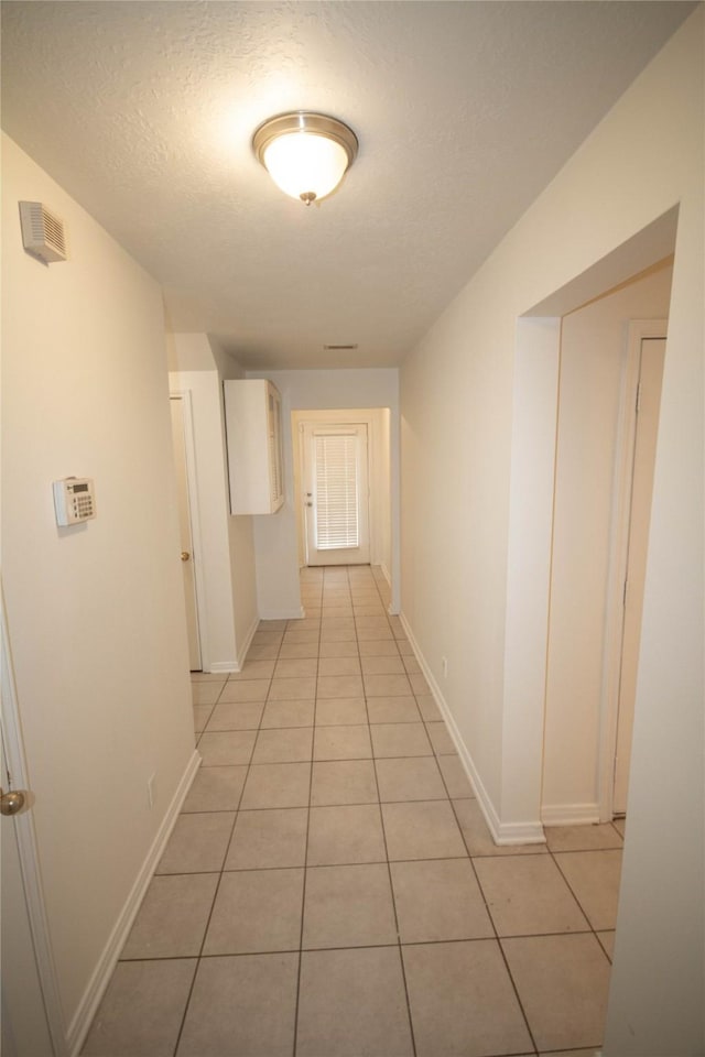 corridor featuring light tile patterned floors and a textured ceiling