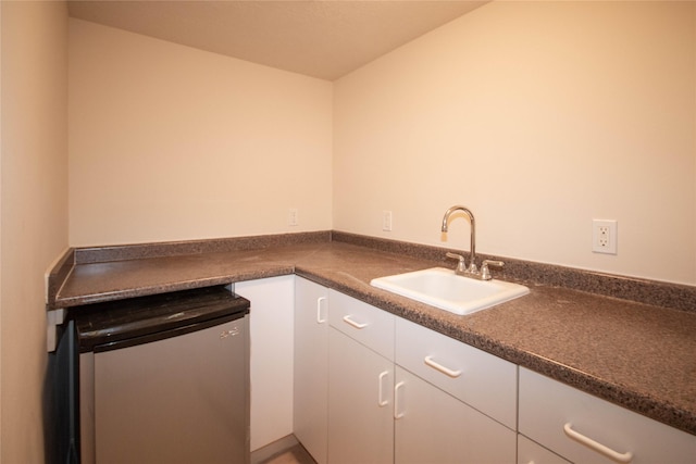 kitchen with white cabinets, refrigerator, and sink