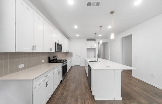 kitchen with white cabinetry, an island with sink, stainless steel appliances, and decorative light fixtures