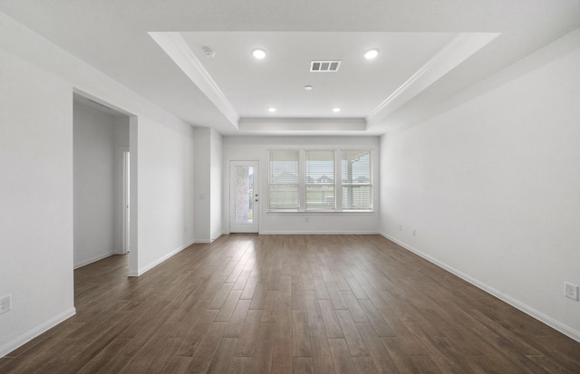 unfurnished room with a tray ceiling, dark hardwood / wood-style floors, and crown molding