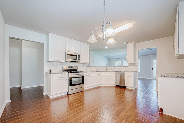 kitchen featuring white cabinets, pendant lighting, wood-type flooring, and appliances with stainless steel finishes