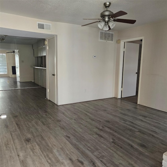 empty room with a textured ceiling, ceiling fan, and dark hardwood / wood-style floors