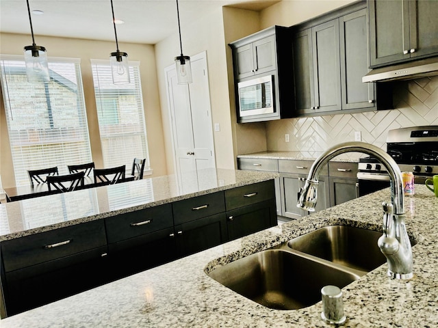 kitchen with sink, hanging light fixtures, tasteful backsplash, light stone counters, and range hood