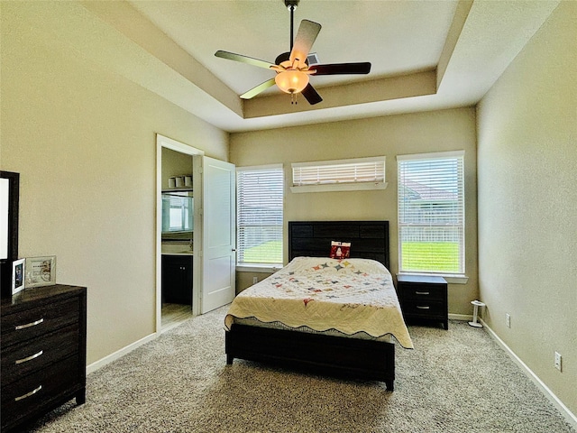 carpeted bedroom featuring a tray ceiling and ceiling fan