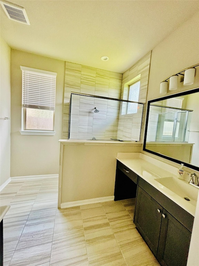 bathroom featuring a tile shower, vanity, tile patterned floors, and a healthy amount of sunlight