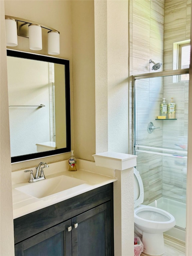 bathroom with a shower with door, vanity, and toilet