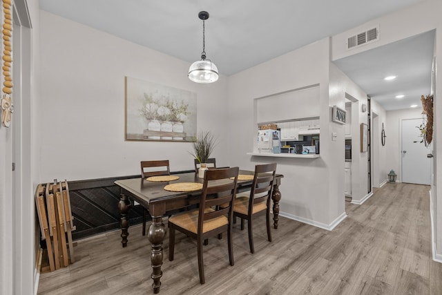 dining room with light hardwood / wood-style floors and an inviting chandelier