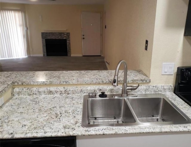 kitchen featuring a fireplace, light stone countertops, and sink