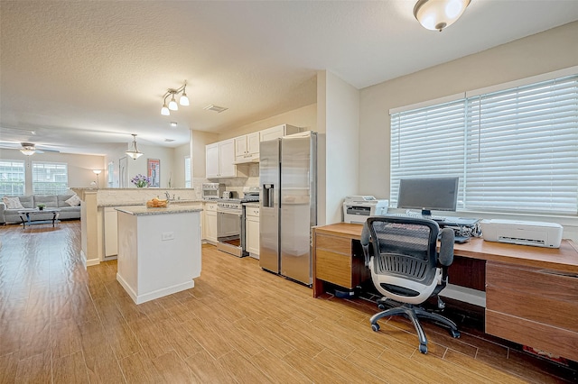 interior space with a textured ceiling, light hardwood / wood-style floors, and ceiling fan