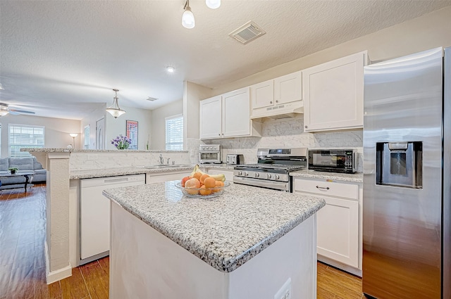 kitchen with a kitchen island, white cabinetry, stainless steel appliances, and hanging light fixtures