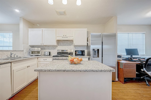 kitchen with stainless steel appliances, a kitchen island, and white cabinetry