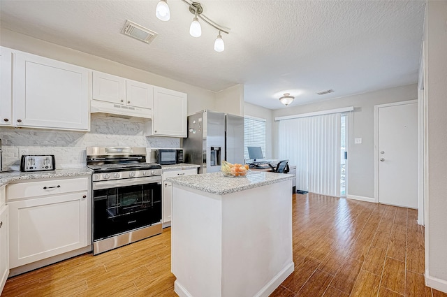 kitchen featuring a center island, white cabinetry, a textured ceiling, and appliances with stainless steel finishes