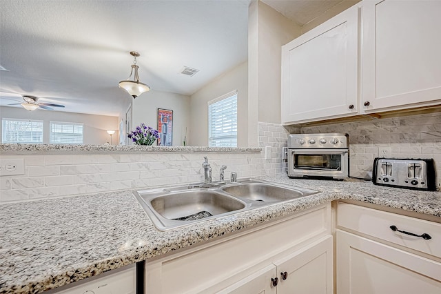 kitchen with backsplash, a wealth of natural light, sink, and white cabinets