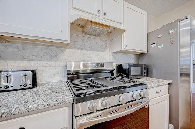 kitchen with white cabinets, light stone countertops, stainless steel appliances, and tasteful backsplash