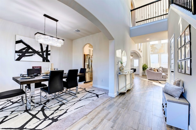 dining area with a towering ceiling and an inviting chandelier