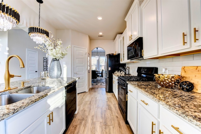 kitchen featuring pendant lighting, black appliances, sink, light stone countertops, and white cabinetry